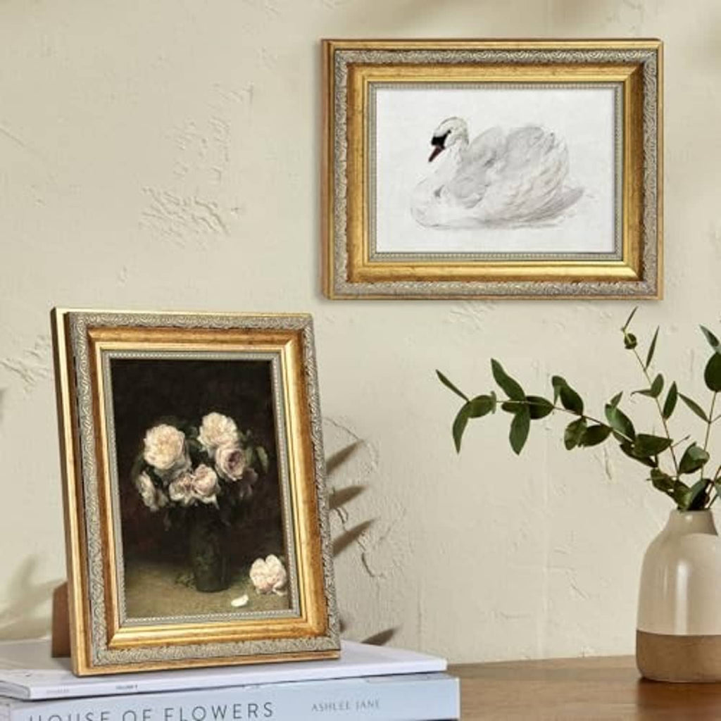 Gold 5x7 picture frame pair on wall with ornate border around clear glass