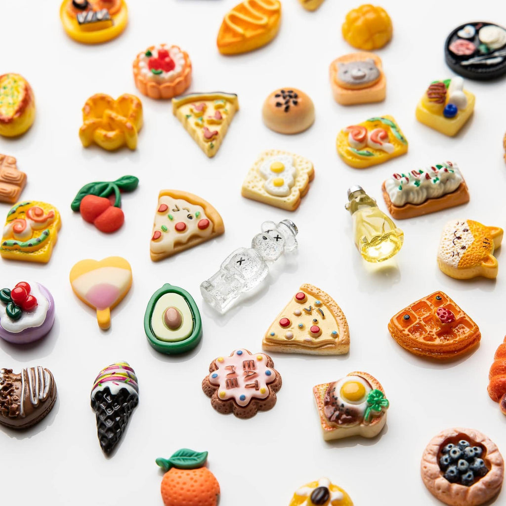 Assorted resin food charms close-up with mini pizza, donuts, cookies, and candy shapes