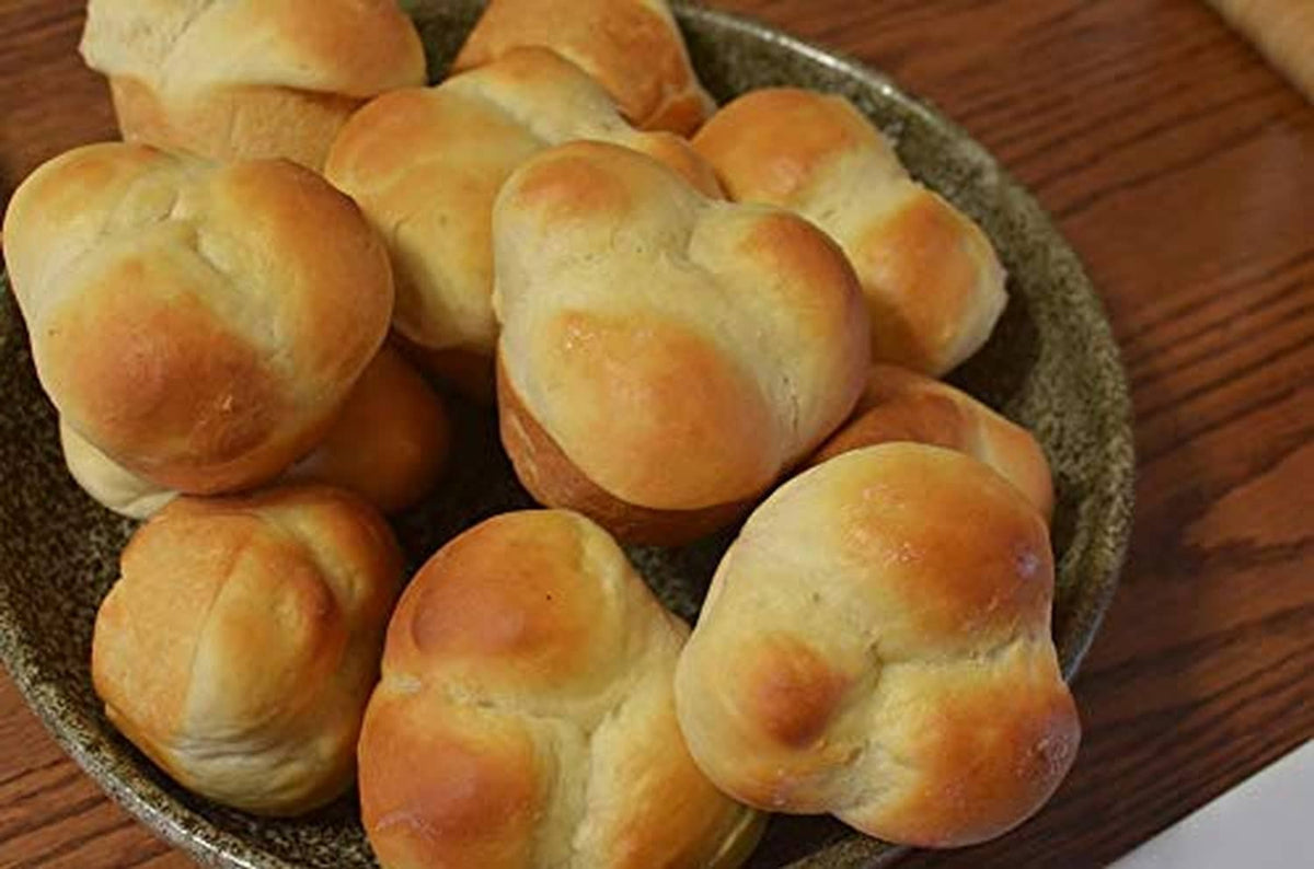 Fresh baked bread rolls in a bowl, golden brown tops and soft rounded shapes.