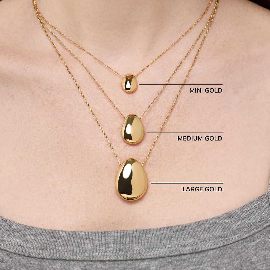 Gold-plated pebble pendant necklace set on chain, three oval pendant sizes