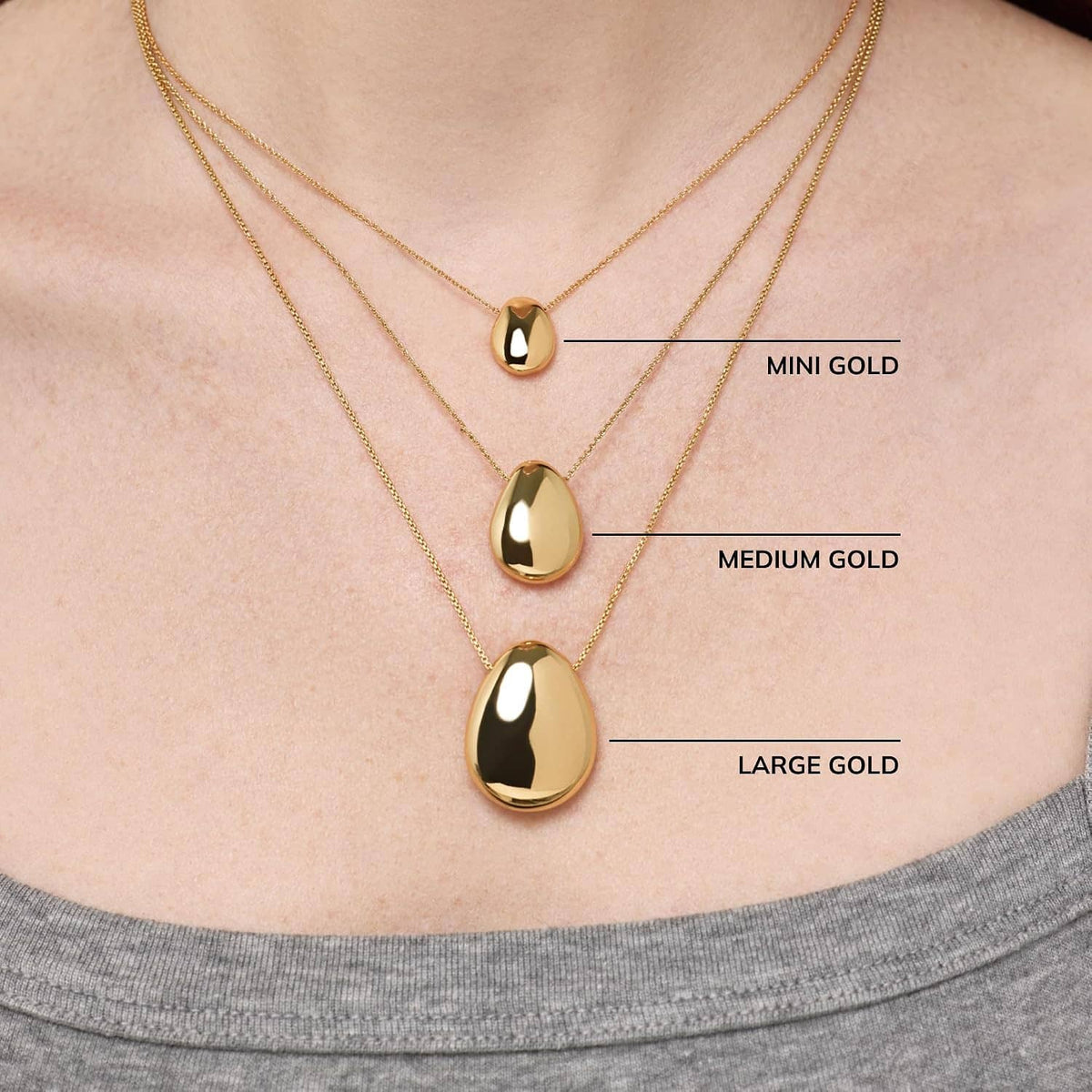 Gold-plated pebble pendant necklace set on chain, three oval pendant sizes