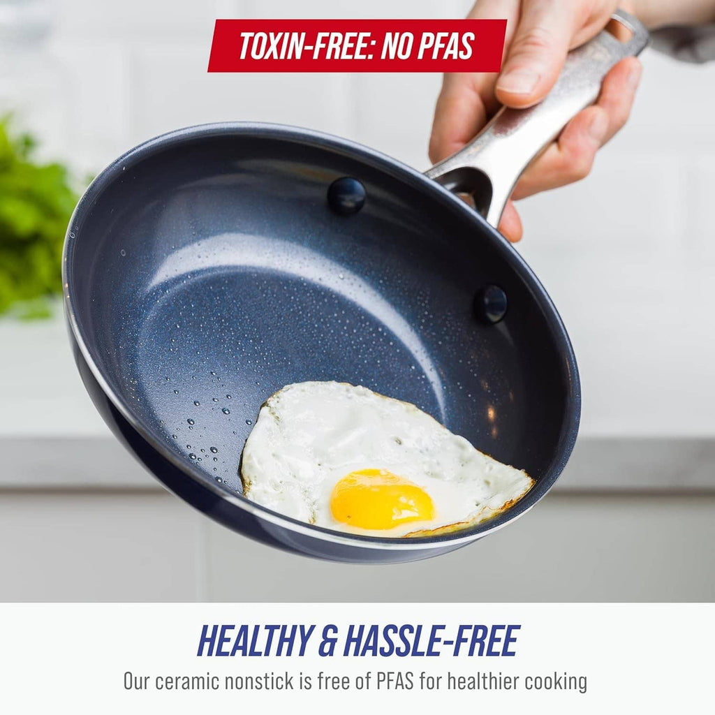 Blue ceramic nonstick frying pan held by a hand with sunny-side egg