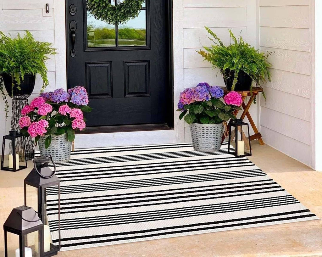 Black-and-white striped woven outdoor rug, rectangular shape with bold horizontal bands.