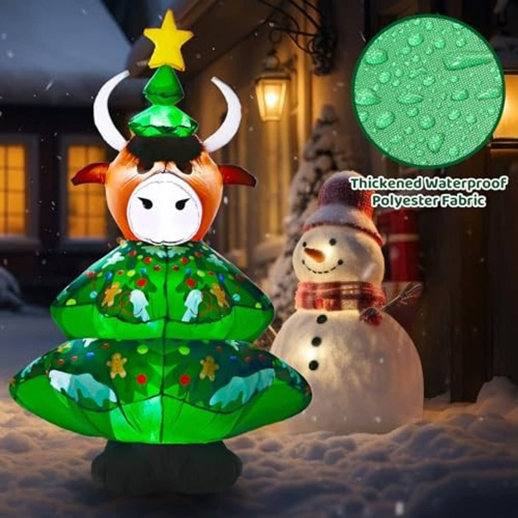 Inflatable highland cow decoration outdoors, green tree outfit and snowman accessory beside it