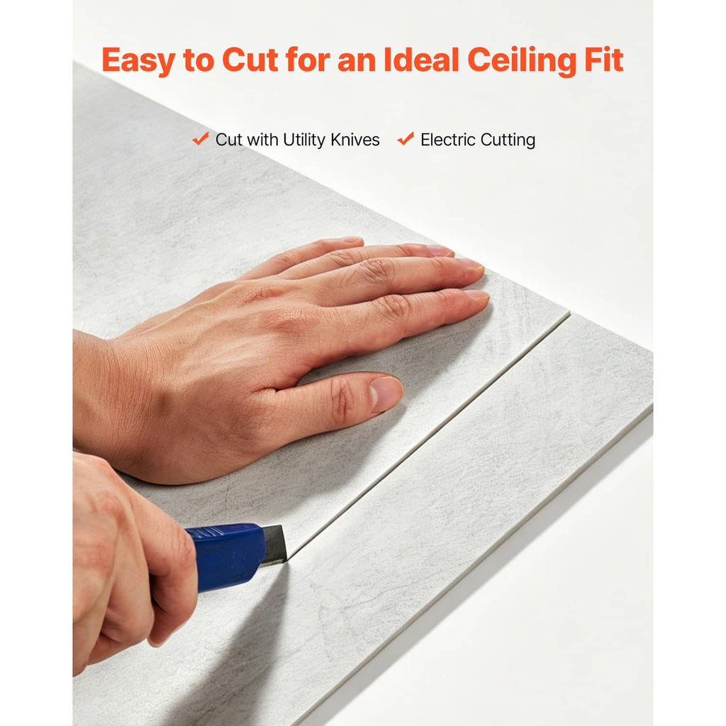 White marble-look PVC ceiling tile being cut with hands, showing panel edge and grid line