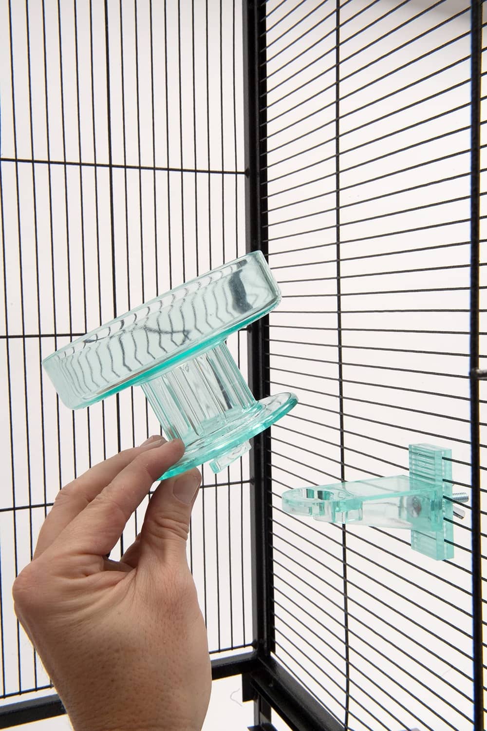 Hand holding turquoise bird bath bracket for wire-cage mounting