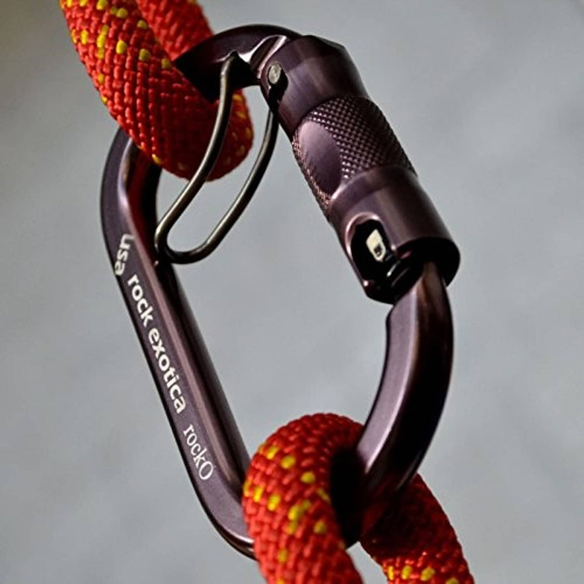 Locking carabiner clip with red rope threaded through curved gate, dark purple body.