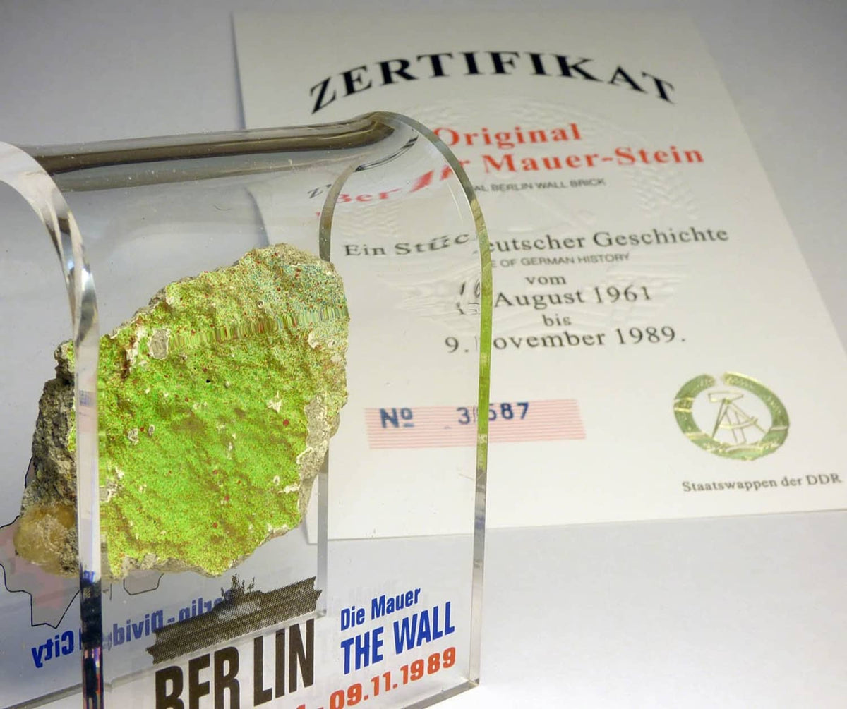Acrylic display case with green rock specimen and certificate card behind glass