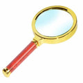 Handheld magnifying glass with gold rim and red handle, wide lens for reading