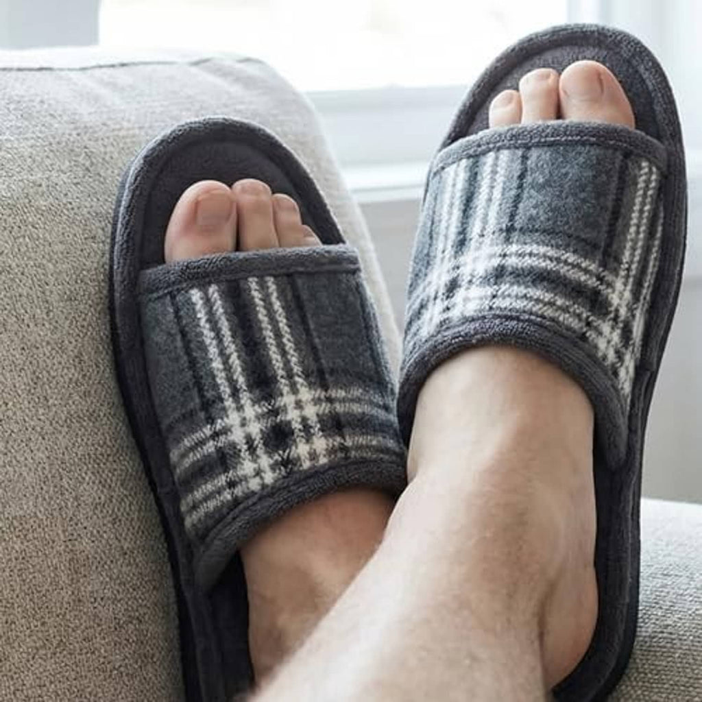 Men's grey plaid open-toe house slippers on feet indoors