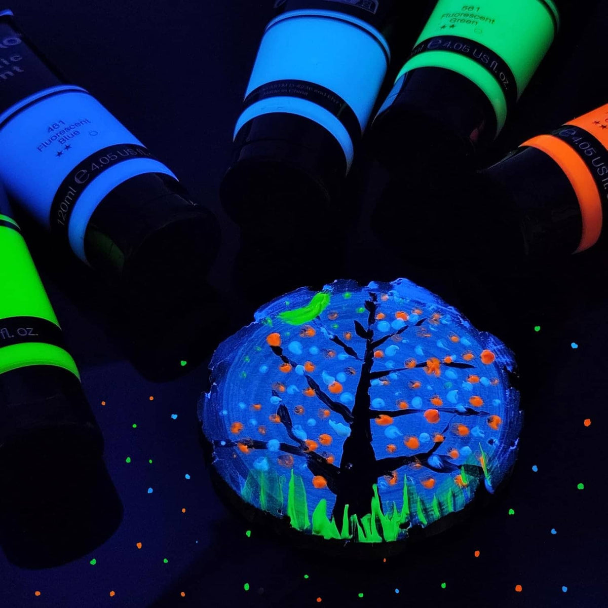 Fluorescent acrylic paint bottles around a glowing night scene globe