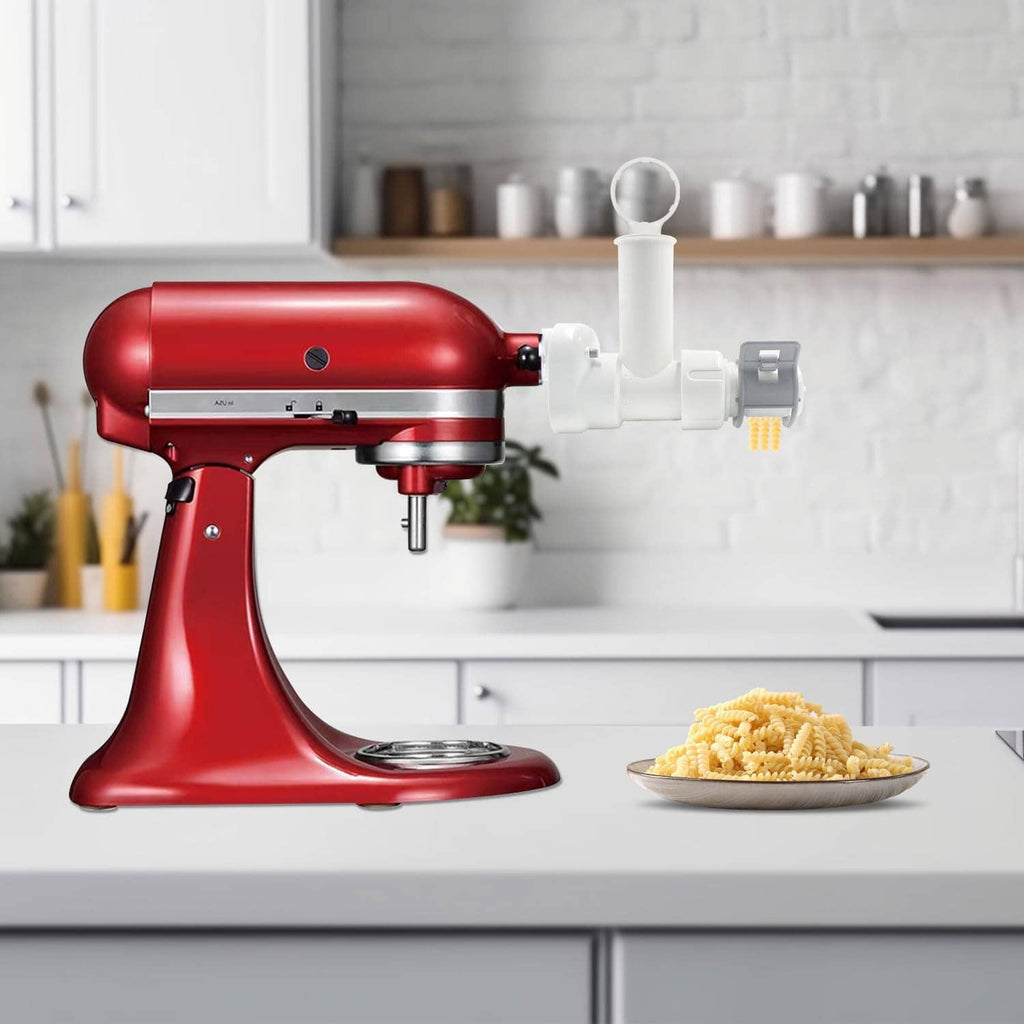 Red KitchenAid stand mixer with attached white pasta maker and serving of cut pasta