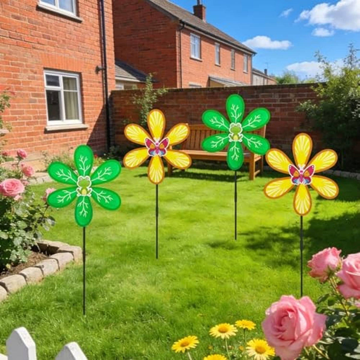 Four outdoor wind spinners with green leaf petals and yellow flower petals on black stakes