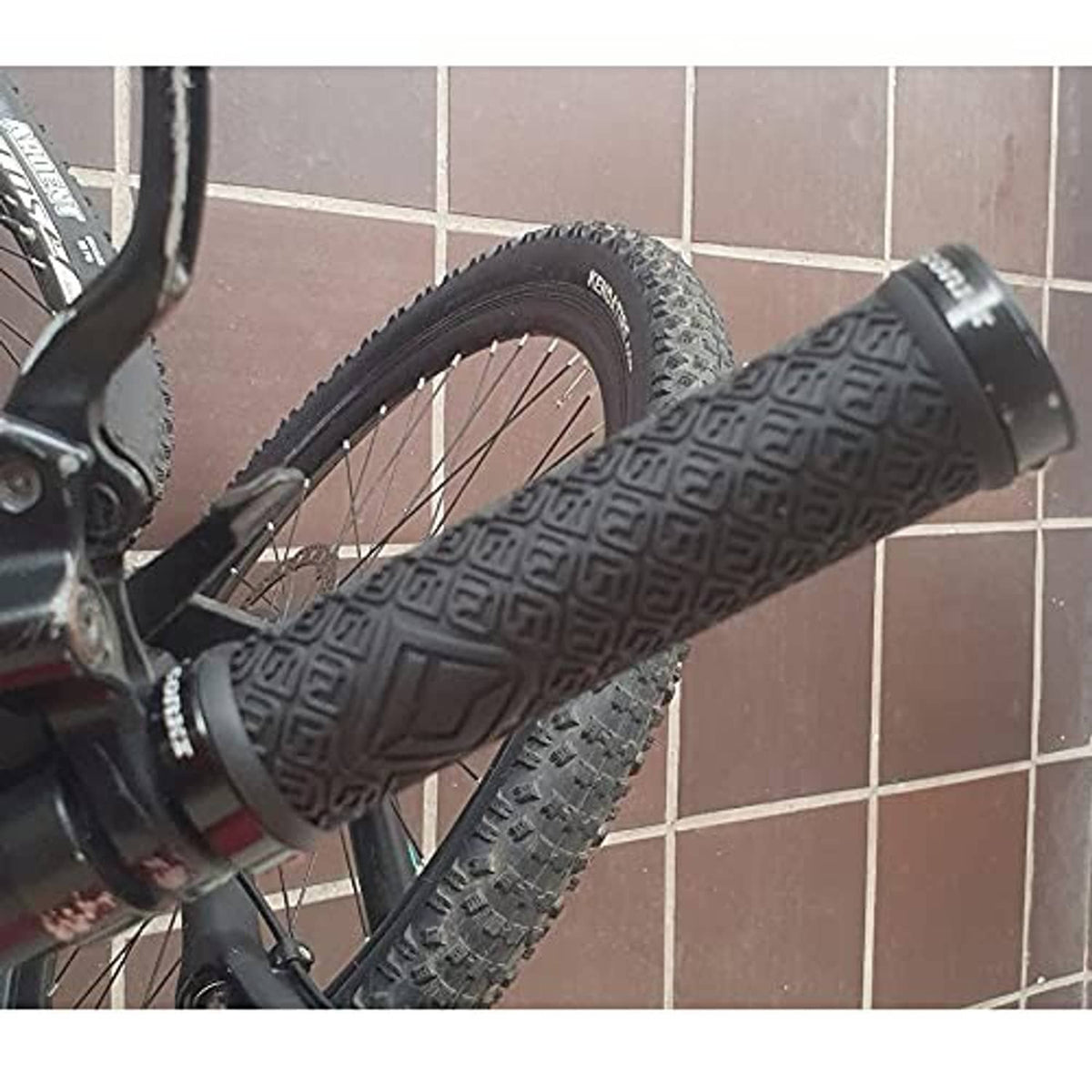 Black bicycle handlebar grips with textured pattern, mounted near the front wheel