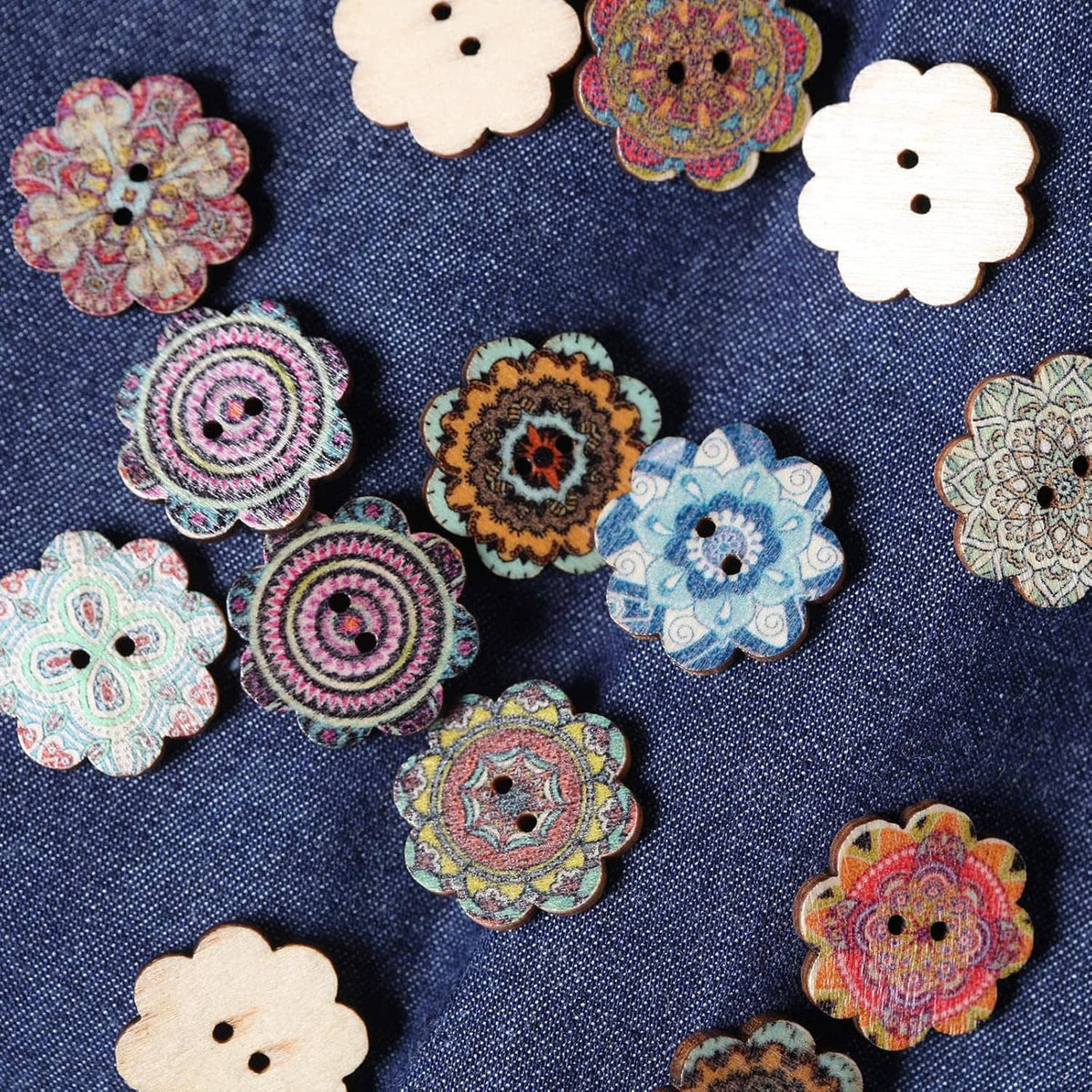 Assorted two-hole wooden flower buttons on blue denim, colorful ornate patterns