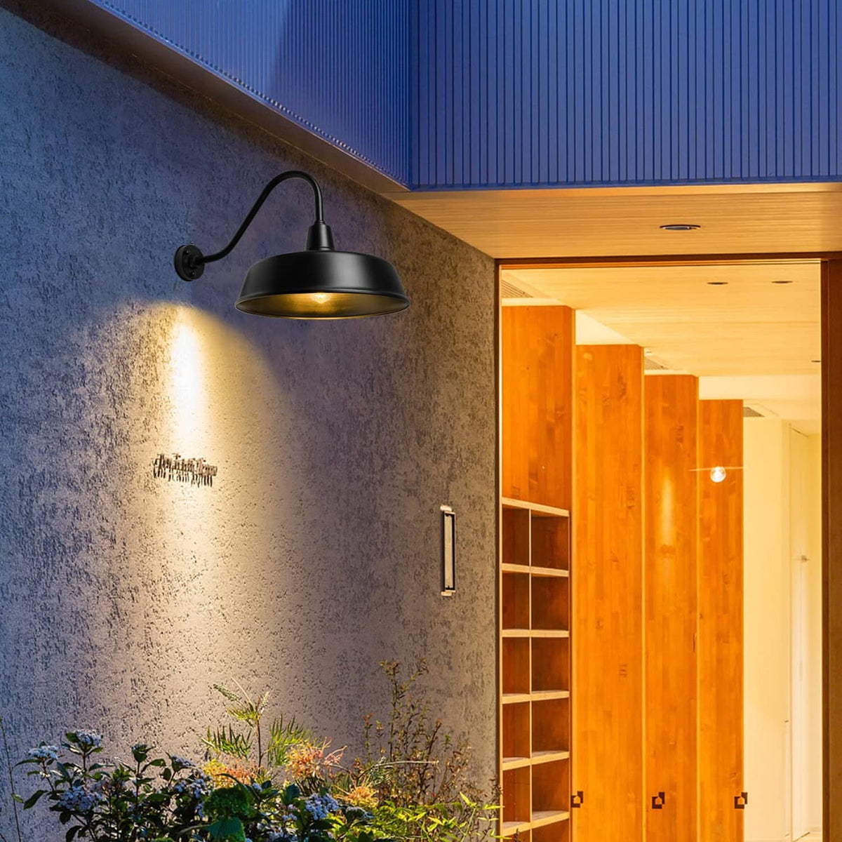 Black exterior gooseneck barn light mounted on wall with warm lit bulb