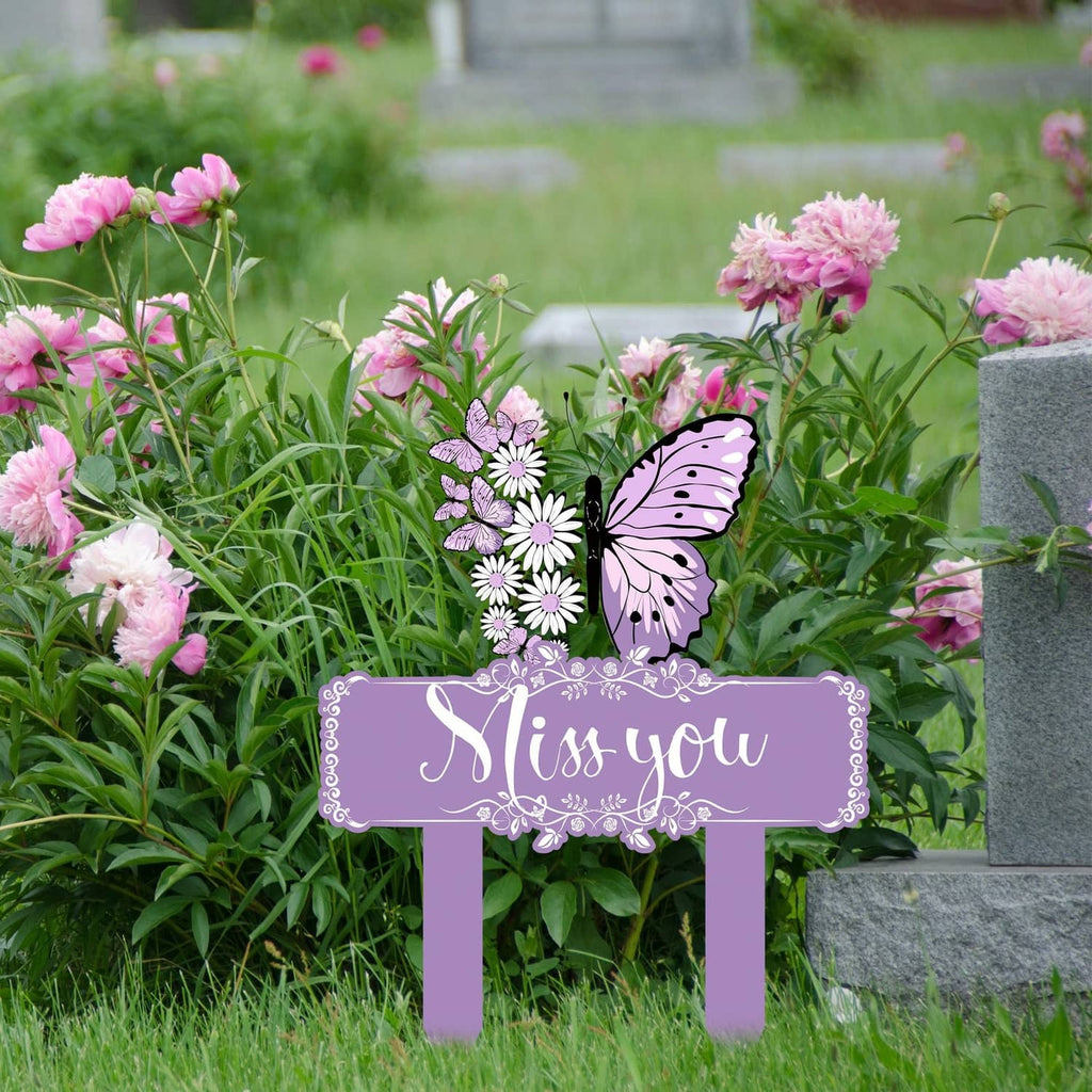 Purple butterfly memorial stake on grave among pink flowers and headstone