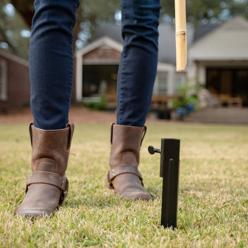 Boots near a black metal torch stake standing in the grass