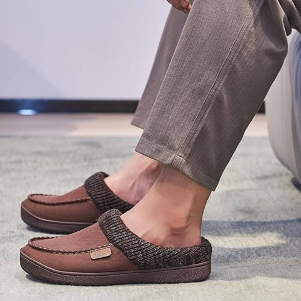 Men's feet wearing brown moccasin clog slippers with dark knit slip-on cuffs
