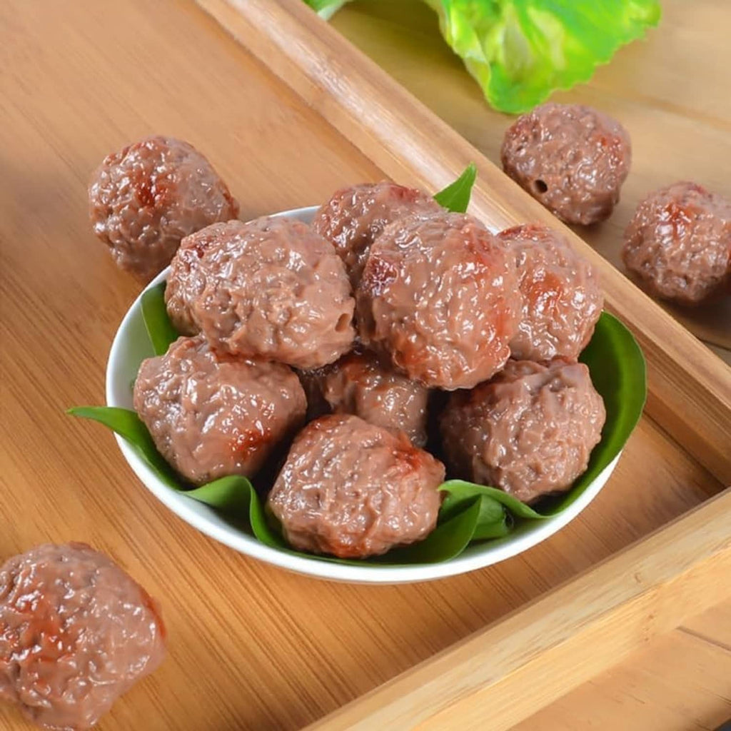 Artificial beef meatballs, brown, piled in a bowl with green leaf accents