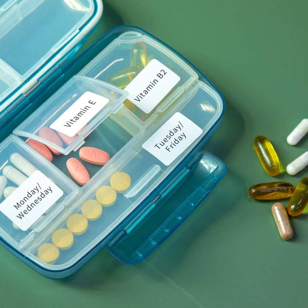 Small printed labels for vitamins and days, placed on a pill organizer