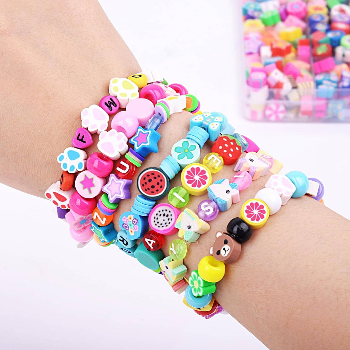 Colorful polymer clay charm bead bracelets stacked on a wrist