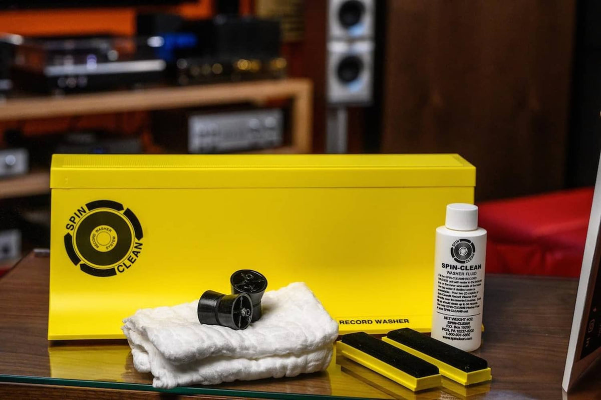 Vinyl record cleaner kit with yellow box, bottle, cloth pad, and brush tools