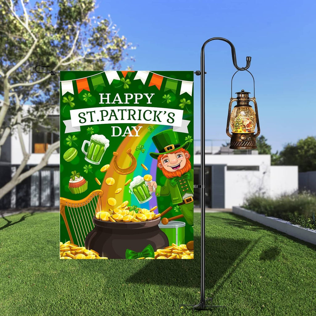 Green St. Patrick's Day garden flag on metal stake beside lantern, leprechaun and pot of gold