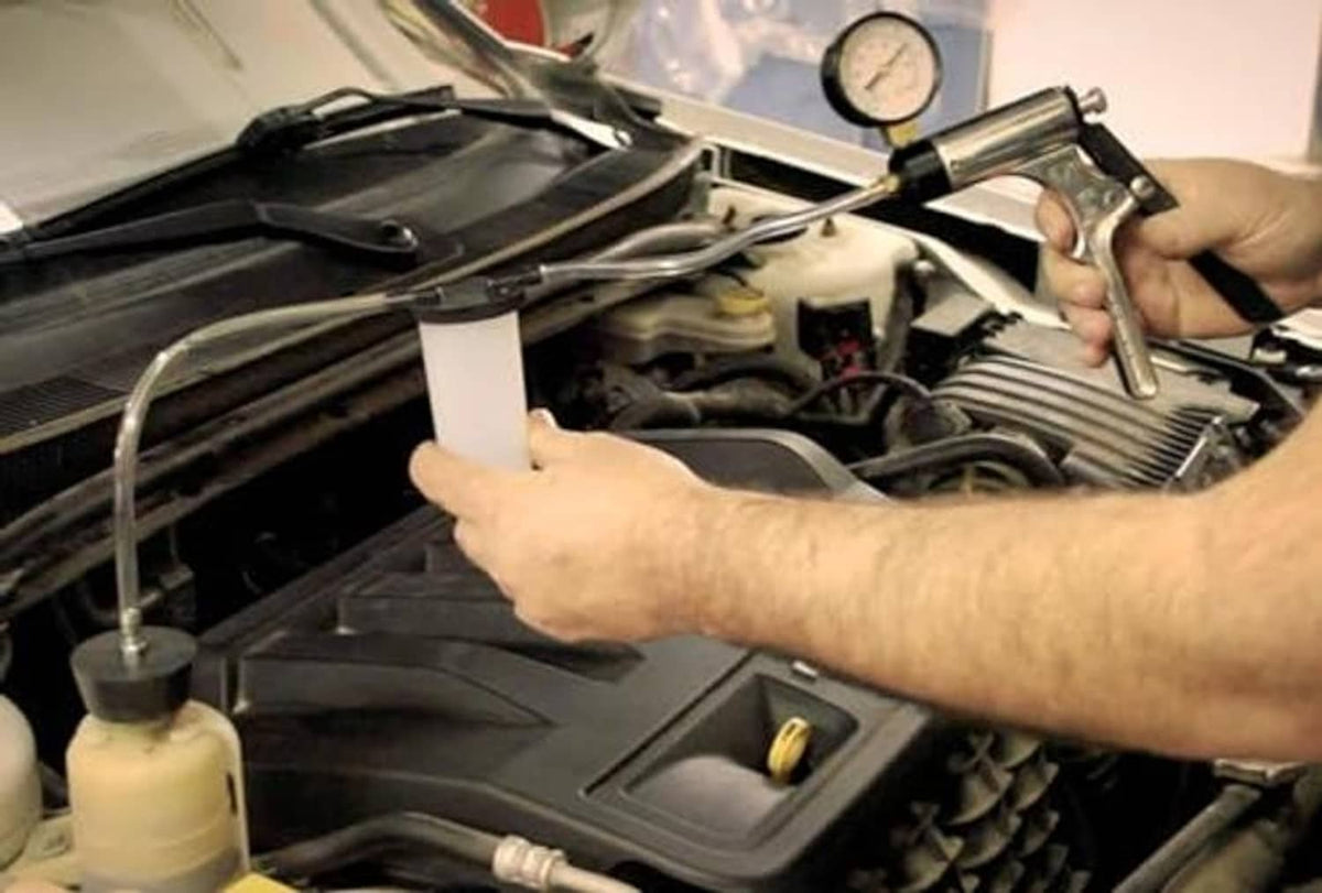 Brake bleeder kit under hood with white fluid cup and clear suction/bleed hose