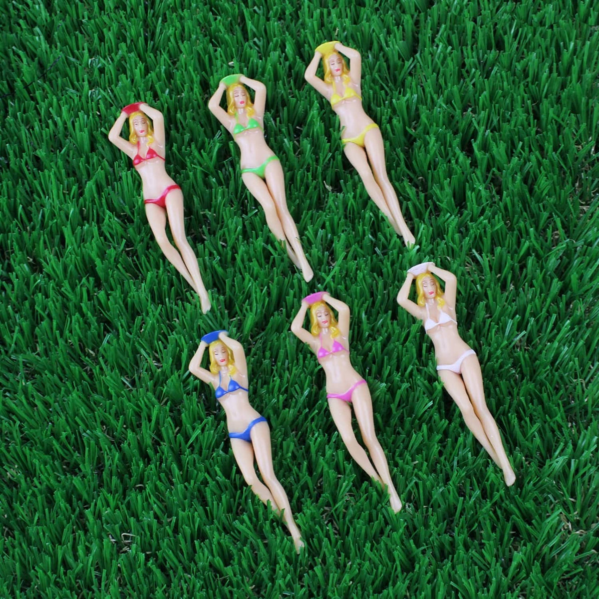 Golf tee set with bikini figurine toppers in red, green, blue on green turf
