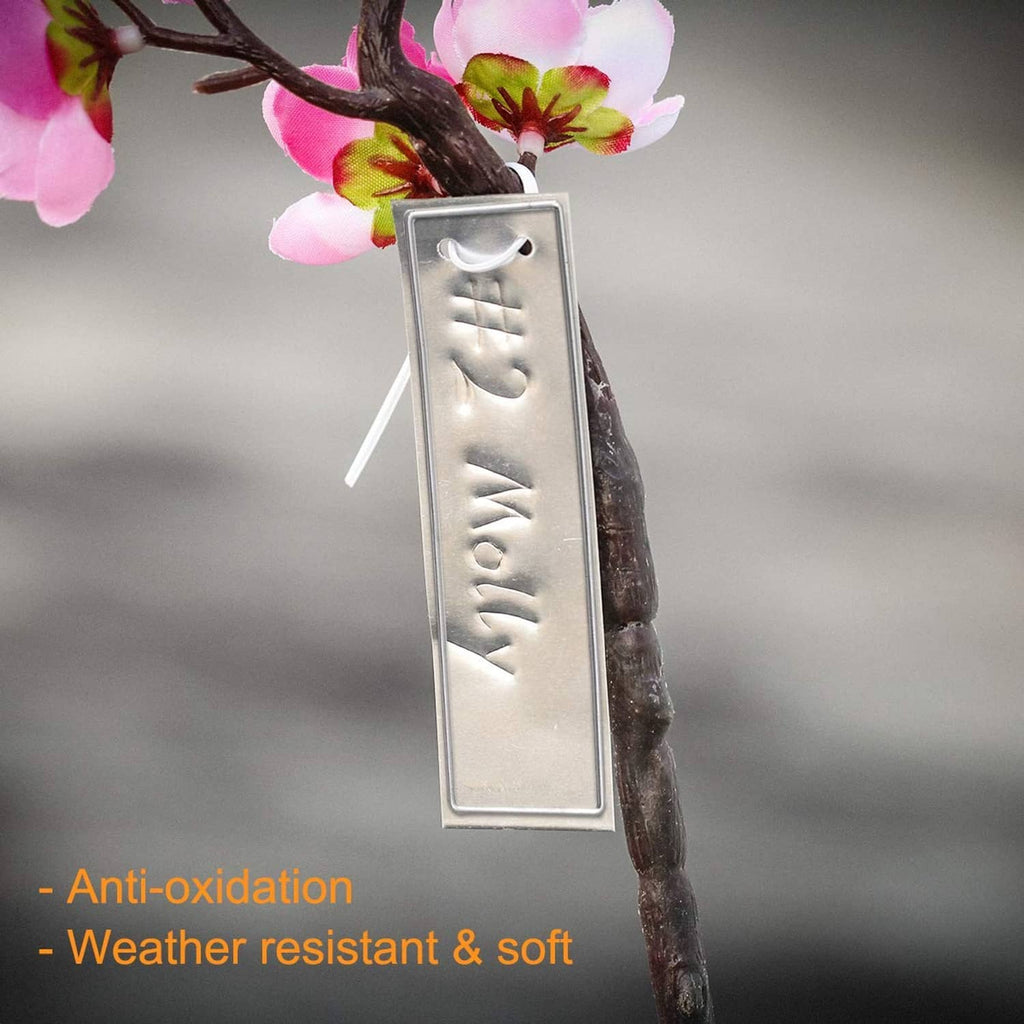 Aluminum plant tag with hanging wire on branch, engraved grooves on the metal plate
