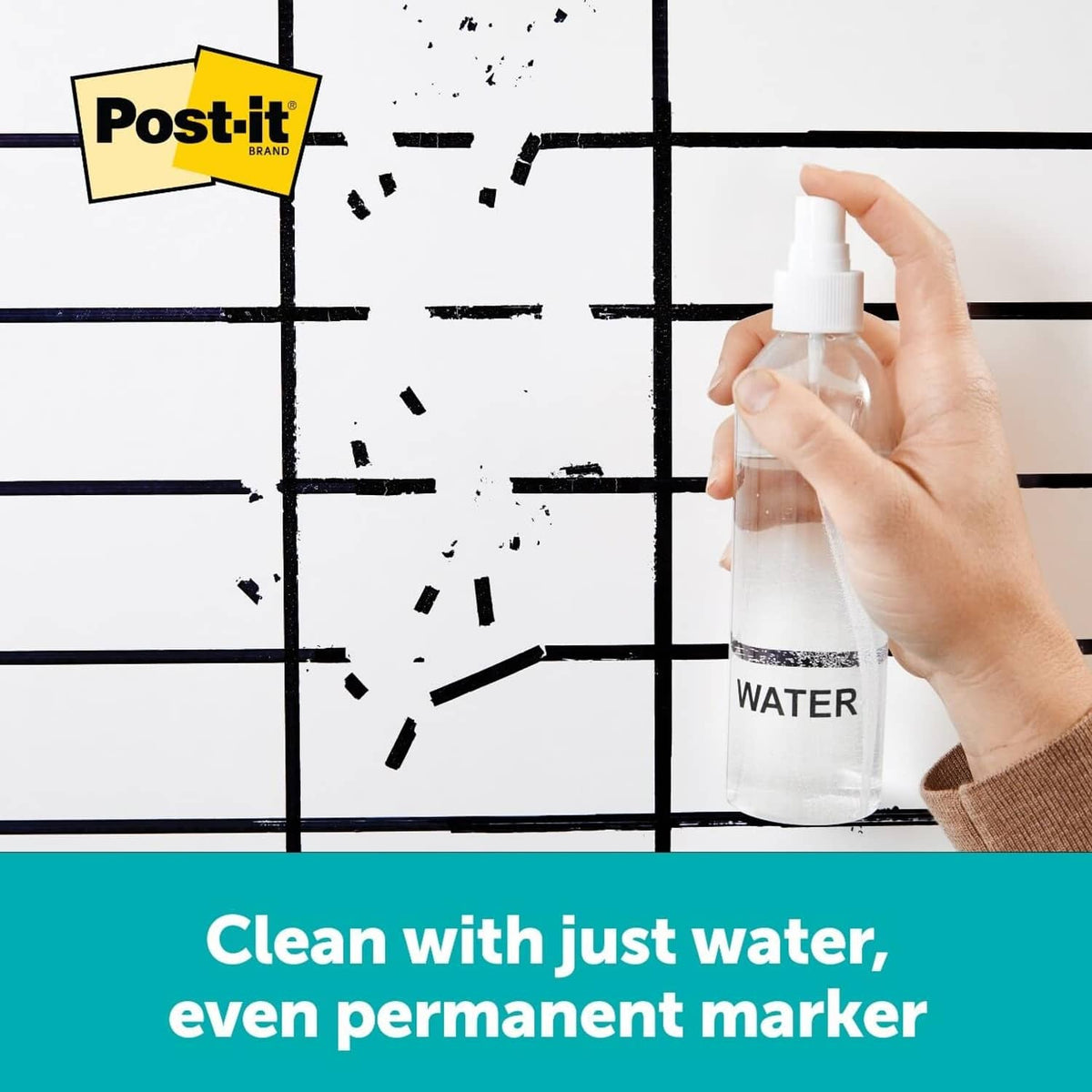 Hand holding spray bottle to clean ink marks on a grid writing surface