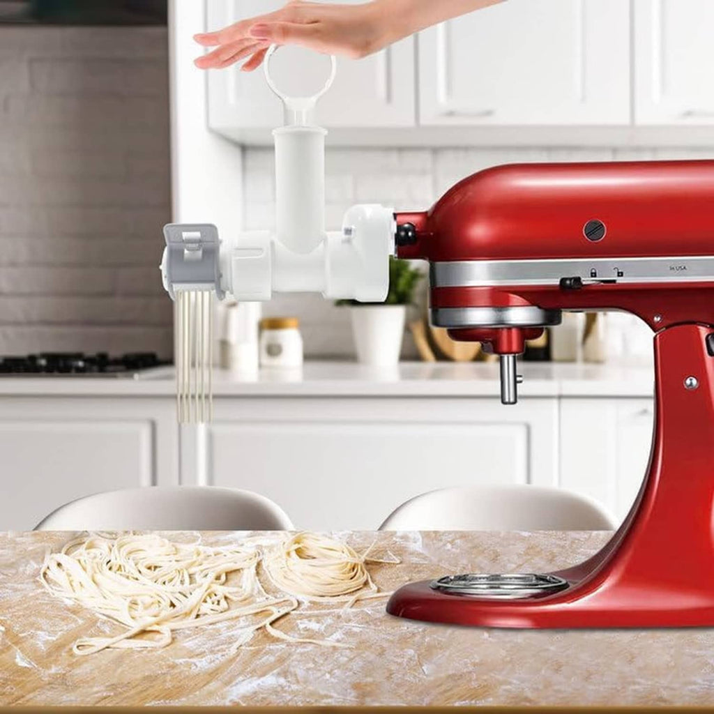 Red KitchenAid mixer with white pasta maker attachment pressing fresh pasta on tray