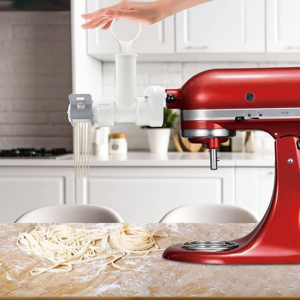 Red KitchenAid mixer with white pasta maker attachment pressing fresh pasta on tray