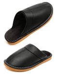 Black leather slip-on slippers with fuzzy lining, rounded toe, and stitched trim