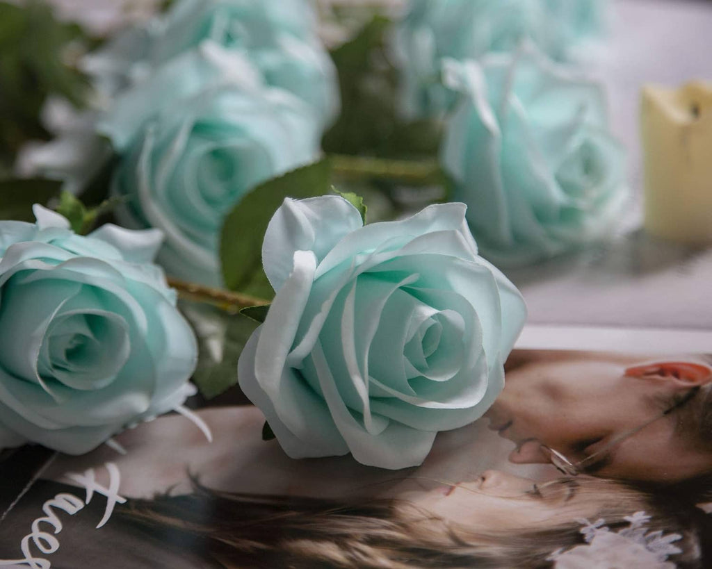 Close-up of teal blue artificial rose flowers with layered petals and green stems