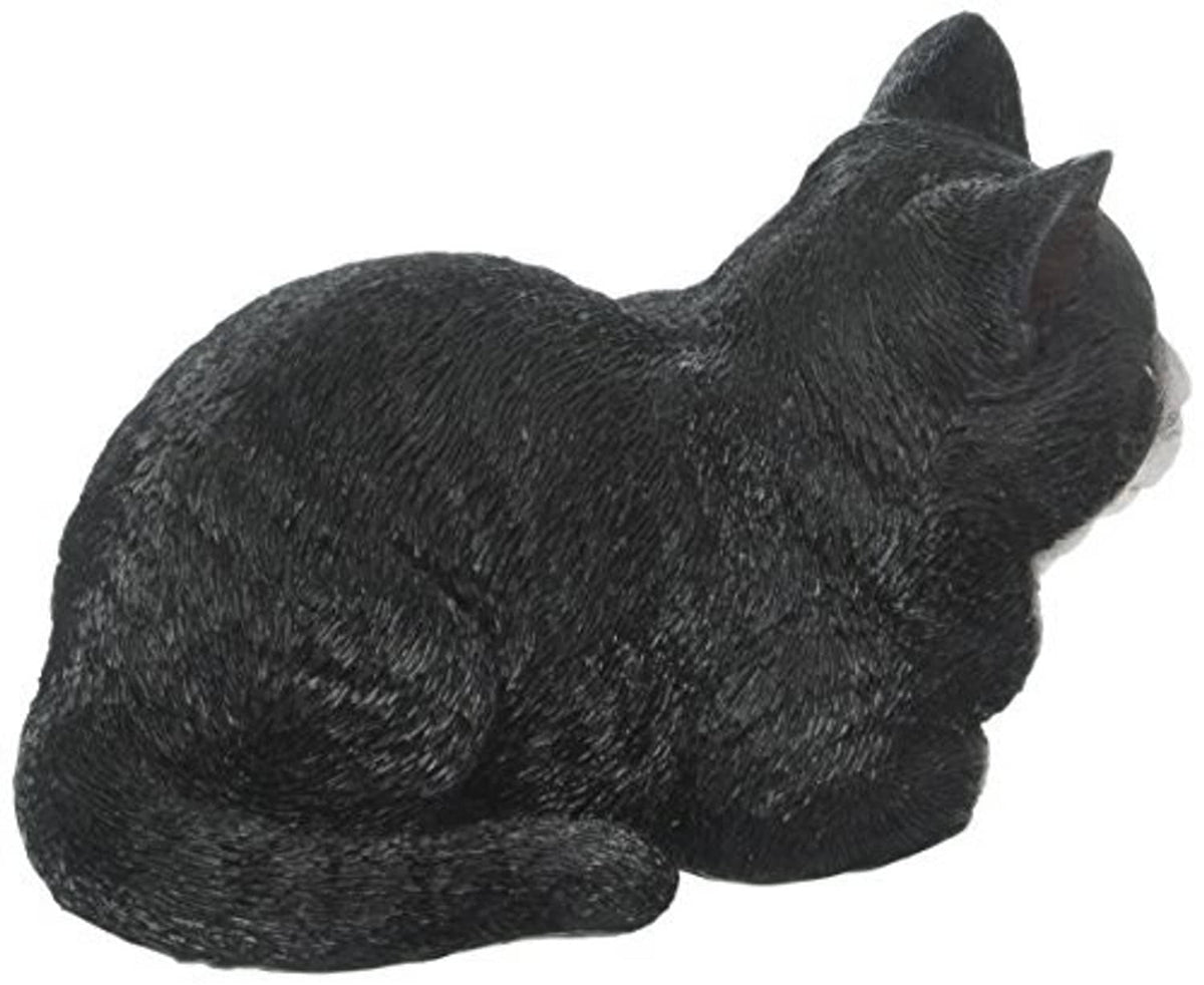 Sleeping cat statue, black with white underside accents, lying on side