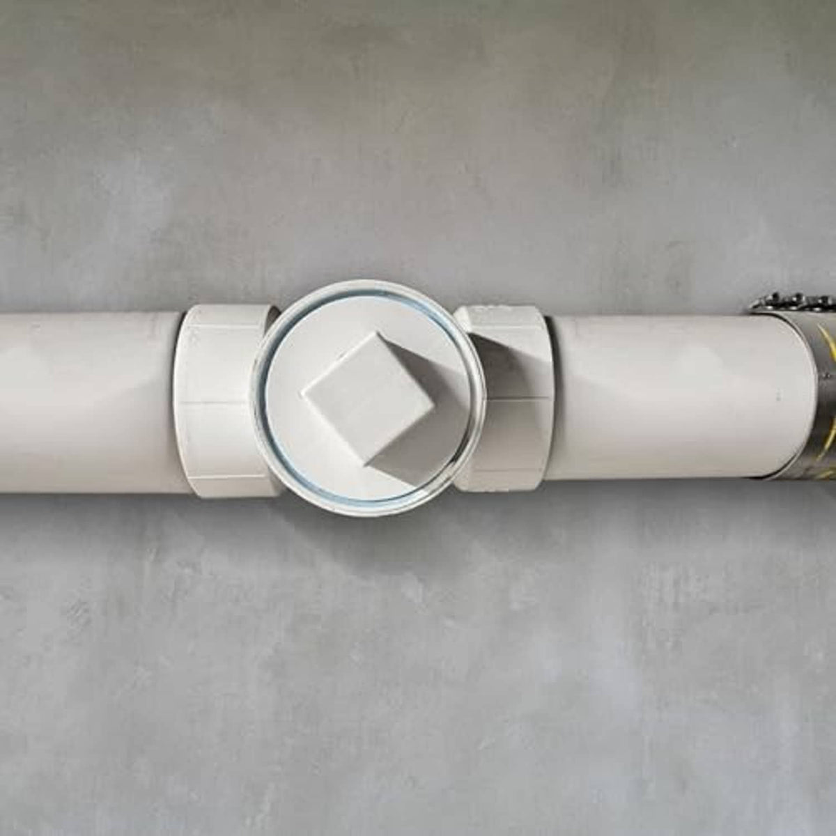White PVC sewer cleanout plug on horizontal DWV pipe, flush square cap detail