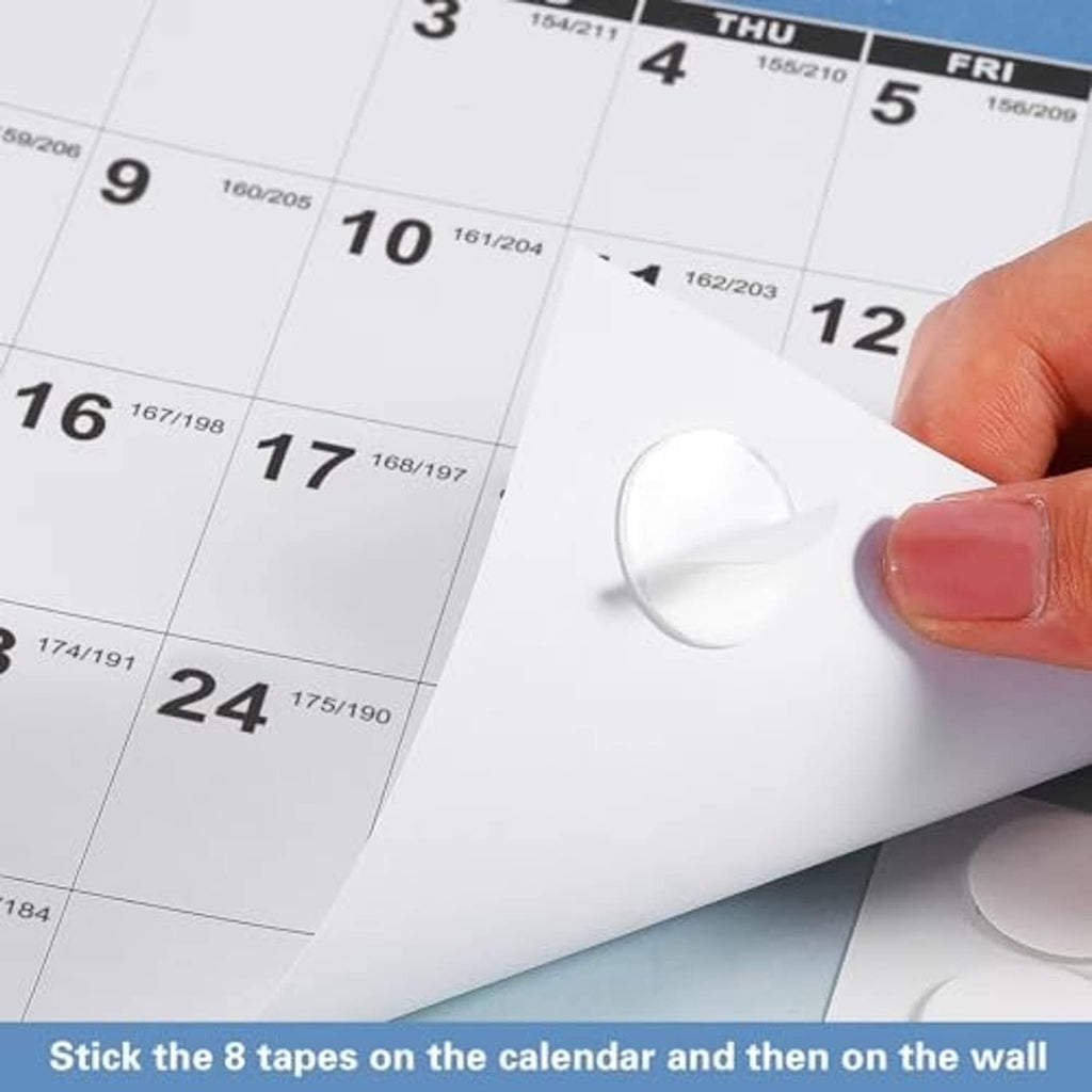 Hand pressing a calendar sticker tape onto a blue 2026-2027 wall calendar