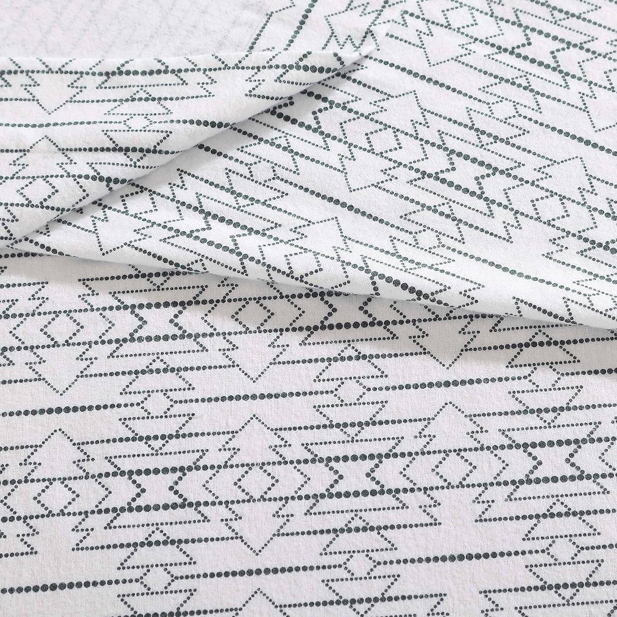 White cotton flannel sheet fabric close-up with navy dotted star and arrow motifs