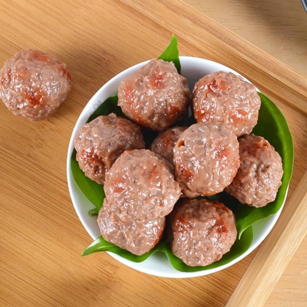 Artificial beef meatballs, brown, in a bowl with green leaf underlayer