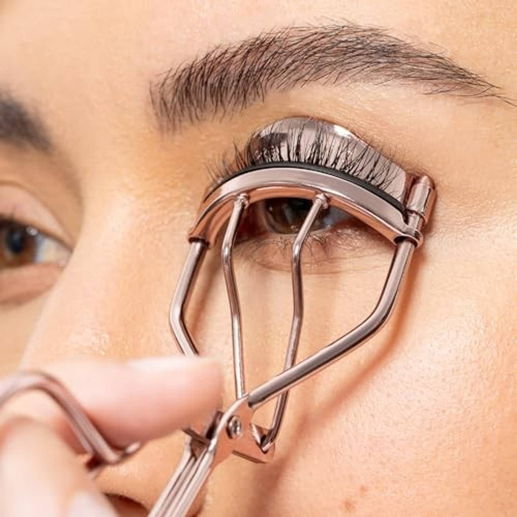 Rose gold eyelash curler clamping lashes near the eye