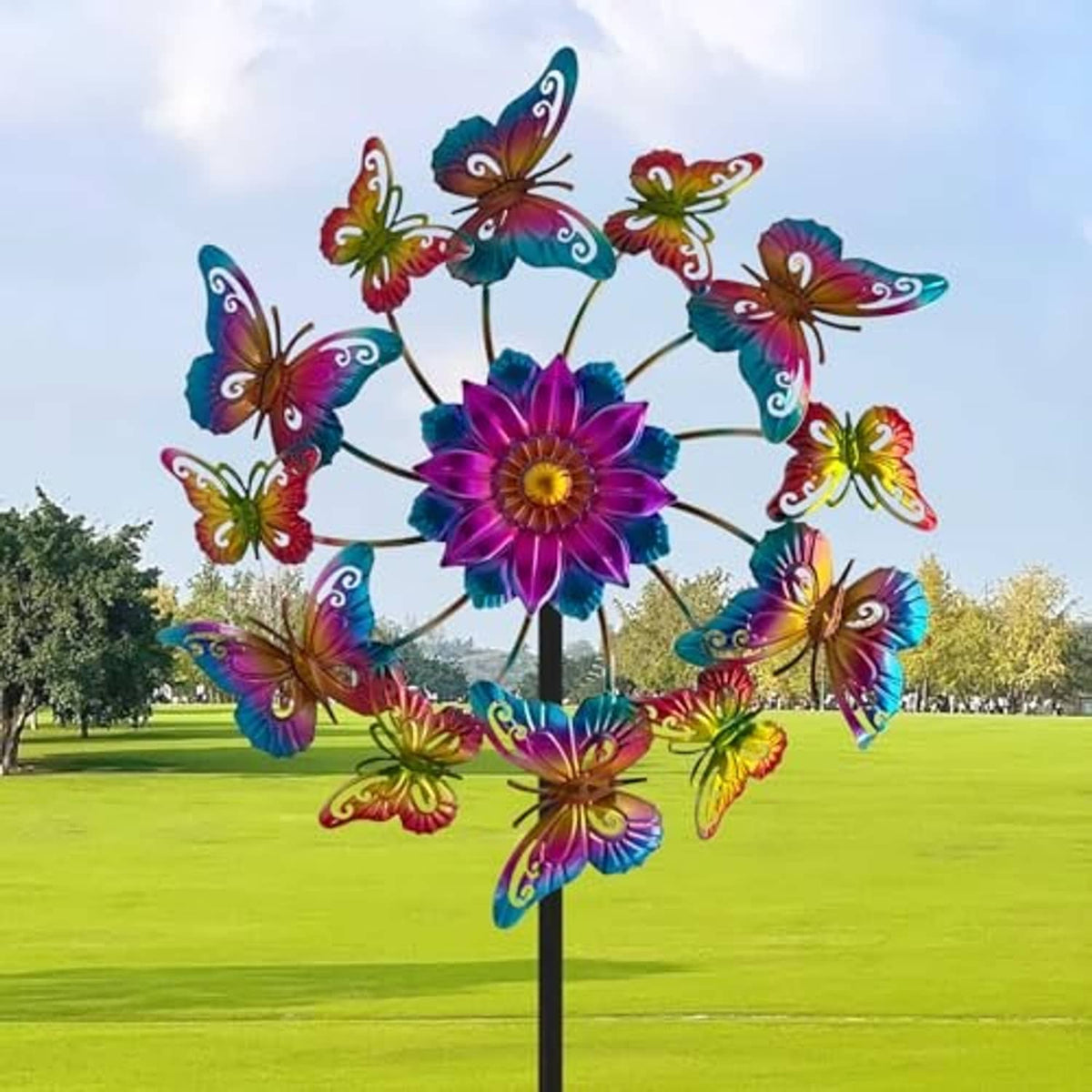 Multicolor butterfly wind spinner flower with curved metal blades on a black yard stake