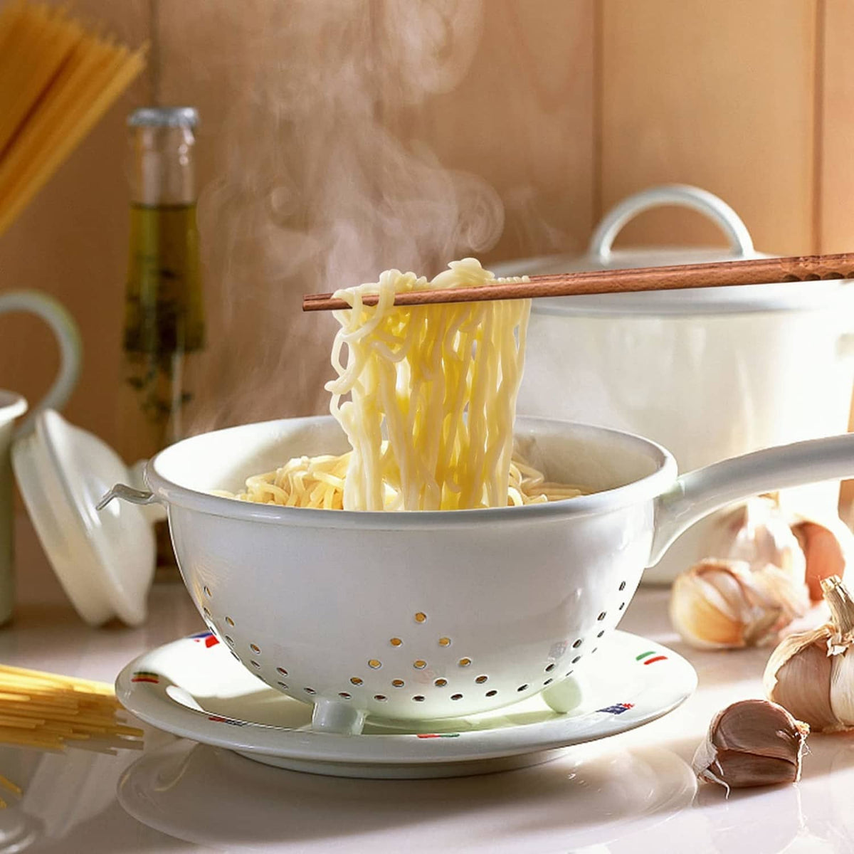 Beech wood chopsticks lifting noodles from a white bowl with perforated insert