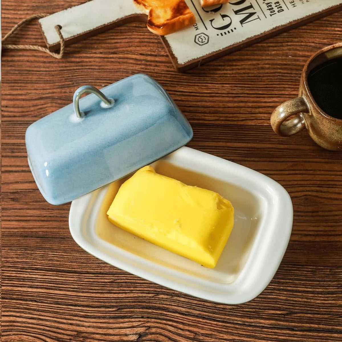 Blue ceramic butter dish with lid open; rectangular tray holds yellow butter