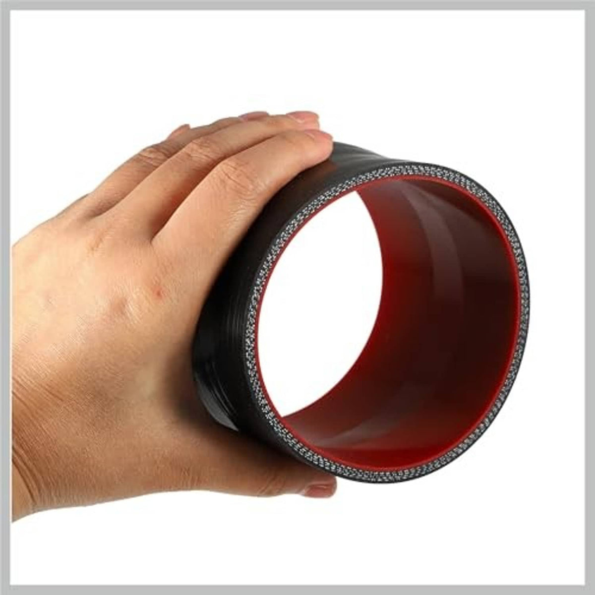 Hand holding silicone hose coupler, black exterior and red interior lining, straight