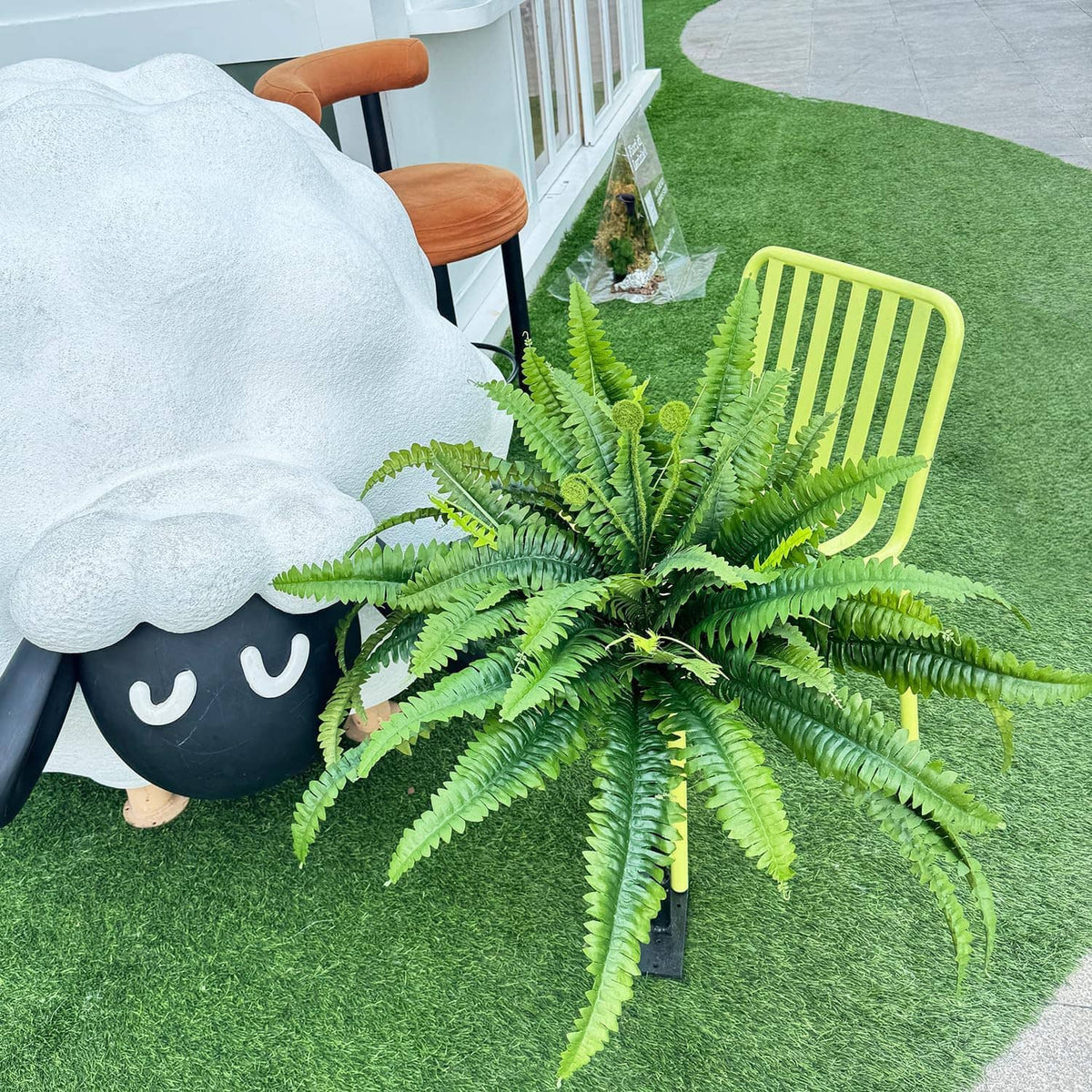 Set of 2 artificial green ferns with long fronds, placed on outdoor turf.