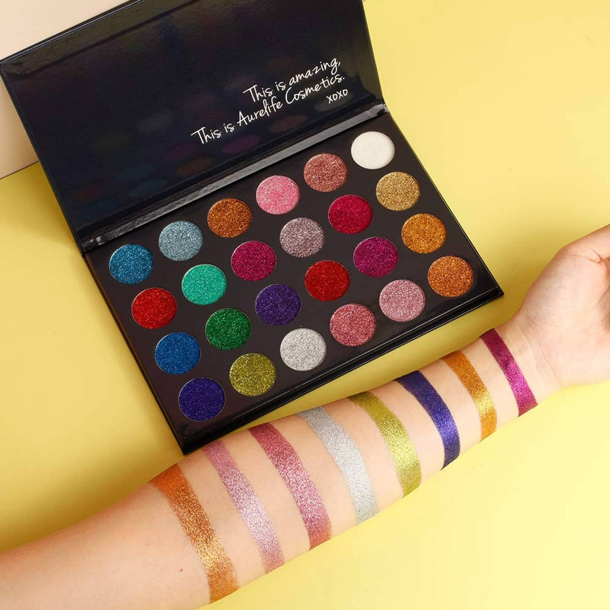 Multicolor pressed glitter eyeshadow palette with glitter swatches on arm, open lid