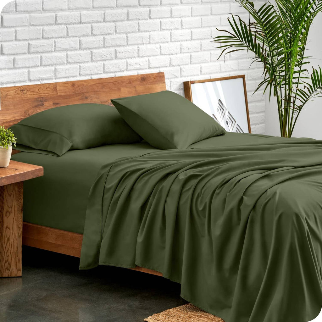 Olive green bed sheet set with pillowcases, draped on a platform bed