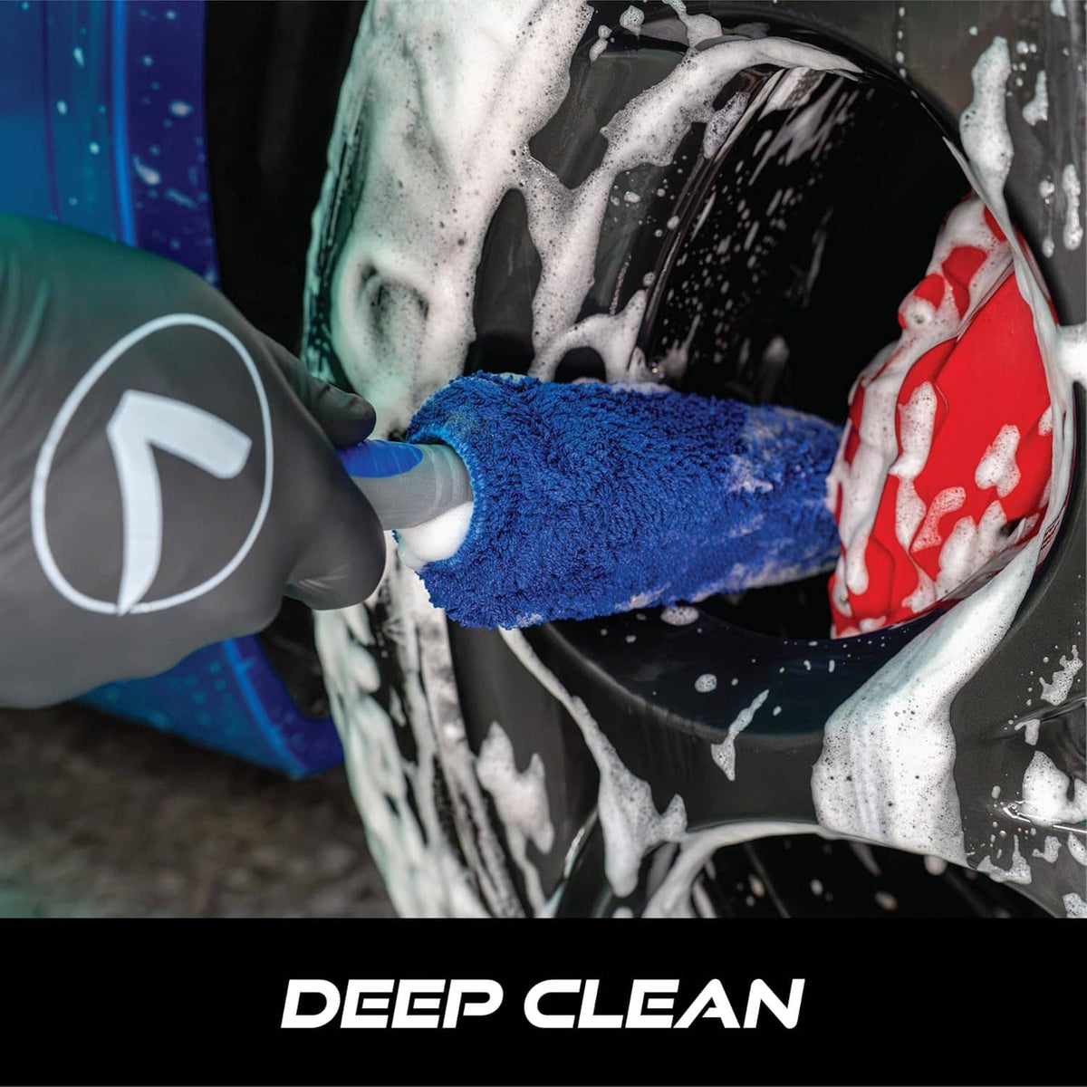 Blue microfiber wheel brush scrubbing a car wheel, removing soap and grime